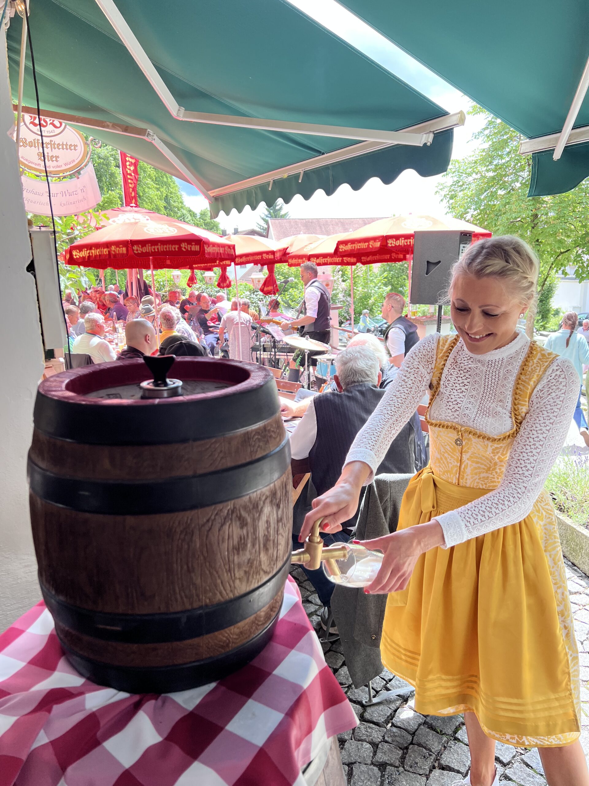 Sonniger Biergarten der Wurz´n in Vilshofen mit roter Fahne, Sonnenschirmen und gemütlichen Holztischen.